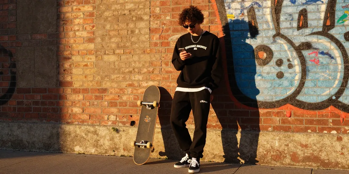 Young fashion enthusiast in Chrome Hearts gear against urban backdrop, showcasing trendy street style lifestyle.